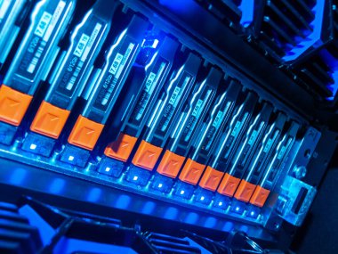 Modern bir sunucu rafındaki canlı mavi LED lambalarla aydınlatılan ileri teknoloji ve tasarım sergilenen yüksek teknoloji veri depolama birimlerinin ayrıntılı görüntüsü.