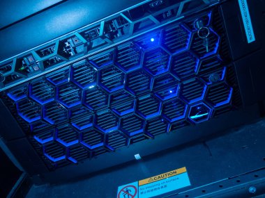 Mavi LED lambaları ve uyarı levhası olan, modern teknolojiyi ve profesyonel bir ortamda gelişmiş tasarım unsurlarını gösteren fütüristik bir raf sunucusunun yakın plan görüntüsü..