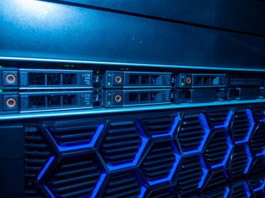 Mavi LED ışıkların yer aldığı modern sunucu ekipmanlarının yakın plan görüntüsü, çağdaş veri merkezlerinde optimum performans için kullanılan karmaşık teknolojiyi gözler önüne seriyor.