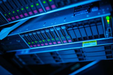 LED göstergeleri olan bir veri depolama sunucusunun yakın görüntüsü, teknolojisini ve tasarımını mavi ışıklı bir ortamda sergiliyor. Teknolojiye odaklı projeler için mükemmel.