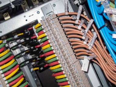 Modern endüstriyel sistemlerin karmaşıklığını ve hassasiyetini gösteren, kontrol panelinde çeşitli bağlantıları olan organize elektrik kablolarının yakın görüntüsü.