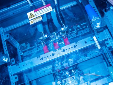 Modern teknolojide kullanılan karmaşık makineleri vurgulayan canlı mavi ışık, kablolar ve uyarı göstergelerini gösteren endüstriyel kontrol panelinin karmaşık bir görüntüsü.