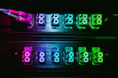 Bu resim renkli elektronik konnektörleri gösteriyor. Karanlık bir ortamda parlak neon ışıklarla aydınlatılıyor. Modern teknoloji ve tasarımı vurguluyor..