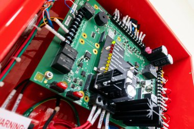 Modern cihazlarla ilgili karmaşık teknoloji ve mühendislik süreçlerini gösteren çeşitli bileşenleri ve renkli kabloları içeren elektronik devre kartının yakın görüntüsü.