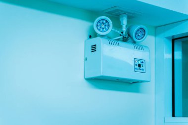 Bir duvara yerleştirilmiş sıkışık acil durum aydınlatma donanımı, çarpıcı mavi bir ortamda LED teknolojisi, çeşitli ortamlarda güvenlik ve aydınlatma için ideal.