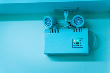 Bu resim, çeşitli ortamlarda gerekli aydınlatmayı sağlayan bir duvara kurulmuş acil durum aydınlatma sistemini içerir. Modern tasarım güvenlik ve işlevselliği vurguluyor.