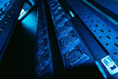 Verimli enerji yönetimi için gerekli olan mavi ışık, kablo ve elektrik bileşenlerini gösteren modern bir veri merkezindeki elektrik dağıtım ünitelerinin ayrıntılı görünümü.