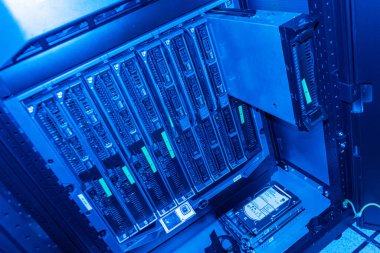 Çok sayıda sunucu ve dijital depolama cihazının yer aldığı, modern bilişim altyapısını vurgulayan, iyi organize edilmiş bir veri merkezi rafı..