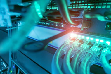 Bu resim, bir sunucuya bağlı ağ kablolarının modern teknoloji ve bağlantıyı vurgulayarak, yumuşak mavi ışıkla aydınlatılmış yakın plan görüntülerini gösterir..