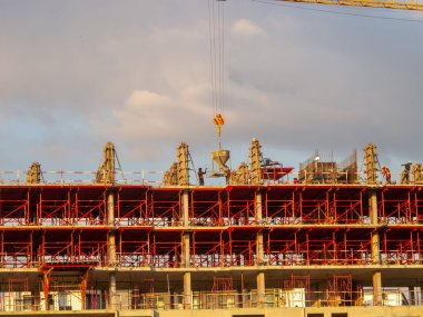Altın saat boyunca bir inşaat sahasının canlı bir görüntüsü, inşaat işçileri beton dökme ve çelik iskelet montajı yapıyorlardı..