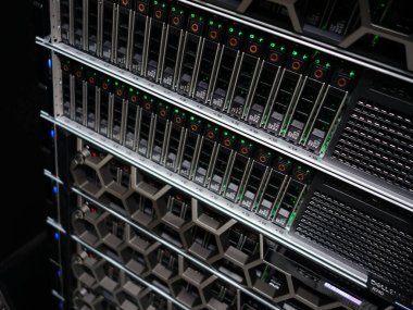 Yanıp sönen ışıklar ve modern tasarıma sahip çoklu birimlere sahip yüksek teknolojili bir sunucu rafının yakın görüntüsü, bir veri tabanında teknolojiyi ön plana çıkarıyor..