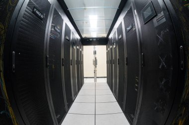 Gelişmiş bilişim altyapısı ve teknolojisinin sergilendiği düzenli bir alanda birden fazla raf sunucusunun yer aldığı modern bir veri merkezinin görüntüsü.