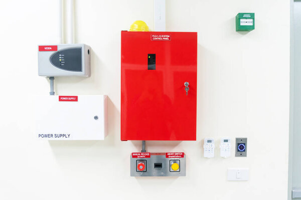 Ярко-красный шкаф управления с блоком питания и аварийными кнопками, установленными на стене промышленного объекта. Essential для управления безопасностью.