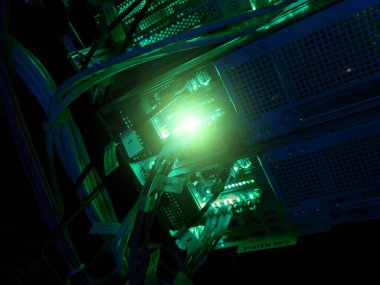 Parlak yeşil LED ışıklar, modern veri yönetimi ve teknoloji için gerekli olan karmaşık kablo ve donanım ağını gösteren yüksek teknoloji sunucu ekipmanlarını aydınlatır.