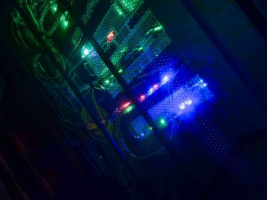 Yüksek teknolojili bir veri merkezinde parıldayan ağ kablolarının büyüleyici bir görüntüsü, karanlık bir ortamda canlı ışıklar ve gelişmiş teknolojiler sergiliyor..