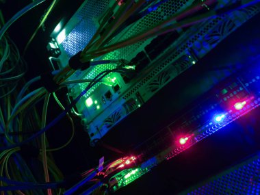 Bir sunucu odasında canlı bir ağ kablosu görüntüsü ve aydınlatılmış ışıklar modern bağlantı ve veri transferini sağlayan karmaşık teknolojiyi sergiliyor..