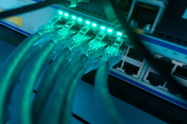 Birbirine bağlı ethernet kablolarını gösteren bir ağ anahtarının ayrıntılı yakın plan görüntüsü, modern altyapıdaki teknoloji ve dijital iletişimi vurguluyor.