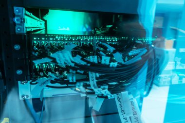 Modern bir veri merkezinde renkli kablolar ve etiketlerle dolu bir ağ rafının yakın plan görüntüsü, gelişmiş teknoloji ve organize altyapı sergileniyor.