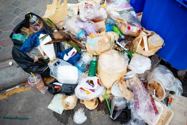 Şehir caddesinde toplanan kaotik bir çöp yığını. Bu resim çöp ve kirlilikle ilgili atık yönetimi konularını ve çevresel kaygıları vurgular.