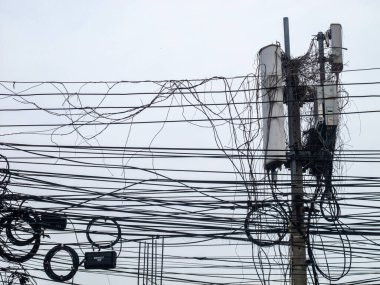 Elektrik hatları ve haberleşme kablolarının gri gökyüzüne karşı düzenlenmesinin detaylı bir görüntüsü, kentsel altyapı karmaşıklığı ve bağlantı zorluklarını gözler önüne seriyor.