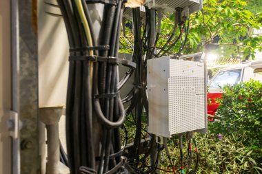 Karmaşık kablolar ile çevrili bir elektrik kutusunun detaylı bir görüntüsü, verimli bir bahçe ortamında teknolojinin entegrasyonunu gösteriyor..