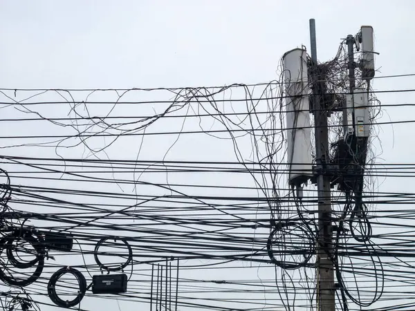 Elektrik hatları ve haberleşme kablolarının gri gökyüzüne karşı düzenlenmesinin detaylı bir görüntüsü, kentsel altyapı karmaşıklığı ve bağlantı zorluklarını gözler önüne seriyor.