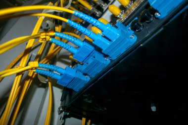 Bir ağ kurulumunda fiber optik bağlantıların ve sarı kabloların detaylı yakın plan görüntüsü, veri transferi ve iletişim altyapısında modern teknolojiyi gözler önüne seriyor.