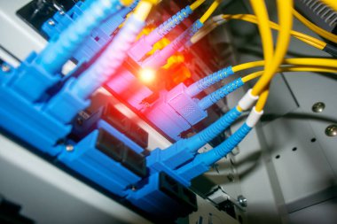 Bir veri merkezinin içindeki renkli fiber optik kabloların yakın görüntüsü. Kablolar kurulumu aydınlatıyor, modern ağ teknolojisi ve bağlantılarını sergiliyor.