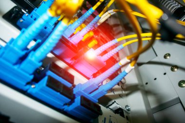 Ağ donanımında fiber optik kabloların yakın görüntüsü, canlı renkler ve aydınlatma, bağlantı ve veri iletiminin modern teknolojideki temel rolünü temsil eden.