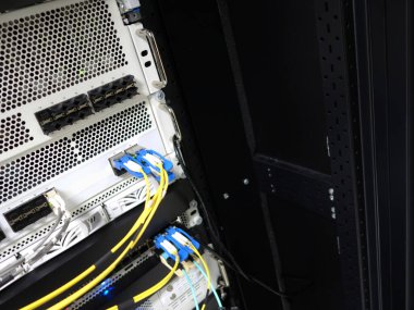 Organize fiber optik kablolar ve ağ bağlantılarının yer aldığı bir sunucu rafının yakın görüntüsü. Bu resim veri yönetim sistemlerindeki modern teknolojiyi vurgular.