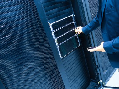 Bir iş adamı bir veri merkezinde gelişmiş sunucu teknolojisiyle etkileşime geçerek, bilişim yönetimi ve dijital altyapının modern işletmelerdeki önemini gözler önüne seriyor..