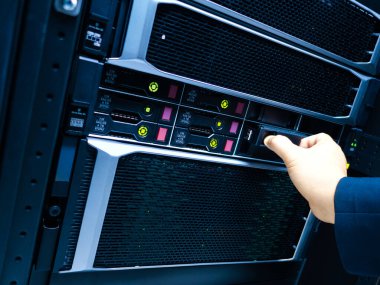 Bir teknisyen, modern bilgi teknolojisi ortamlarında bakım ve işletimin önemini gösteren bir veri merkezinde sunucu yönetiyor..