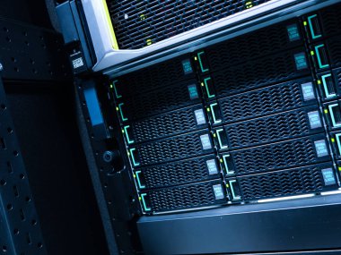 Modern bir veri depolama rafının yakın plan görüntüsü çoklu sabit diskleri gösteriyor. Bu resim etkin veri yönetimi için veri merkezlerinde kullanılan karmaşık teknolojiyi vurgular.