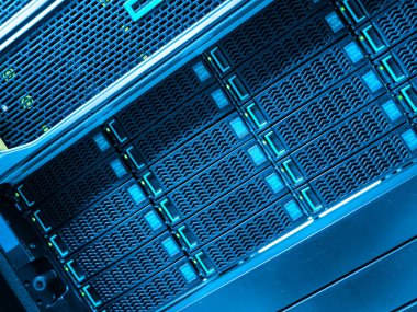 Yüksek teknolojili depolama birimlerini gösteren bir veri merkezi sunucu rafının yakın görüntüsü. Mavi ışıklandırma veri işlemede kullanılan gelişmiş teknolojiyi vurgular.