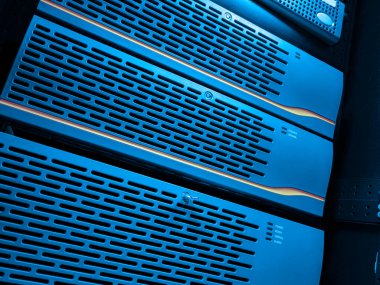 Modern bir veri merkezinde mavi ışıklı bir sunucu rafının yakın plan görüntüsü, gelişmiş teknoloji ve verimli veri depolama ve yönetim için organize donanım sergileniyor.