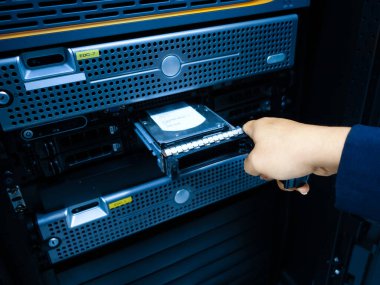 Bir el, veri depolama ve sistem bakımıyla ilgili karmaşık teknolojiyi gösteren bir sabit diski dikkatlice sunucudan çıkarıyor..