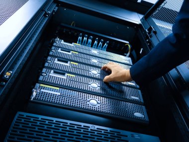 Bir teknisyen modern bir veri merkezinde sunucu bakımını yapıyor. Çevrede gelişmiş teknoloji ve verimli donanım yönetim sistemleri sergileniyor.