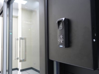 Bir veri merkezine güvenli giriş için tasarlanmış biyometrik parmak izi tarayıcısı ve tuş takımı içeren modern bir erişim kontrol sisteminin resmi.