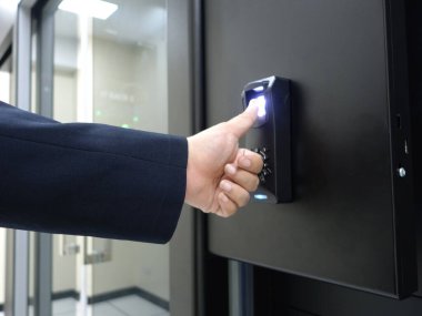 Modern güvenli erişim kontrol sisteminde parmak izi tarayıcısı kullanan bir el. Çeşitli ortamlarda güvenlik ve kolaylık için biyometrik teknolojinin vurgulanması.