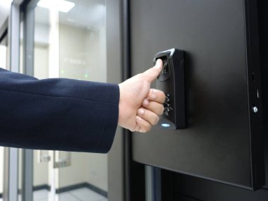 Modern ofis ortamında güvenli erişim için parmak izi tarayıcısı kullanıldığını gösteren bir el, güvenlik sistemlerindeki teknoloji ve kullanıcı etkileşimini vurguluyor.