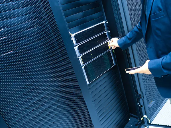 Bir iş adamı bir veri merkezinde gelişmiş sunucu teknolojisiyle etkileşime geçerek, bilişim yönetimi ve dijital altyapının modern işletmelerdeki önemini gözler önüne seriyor..