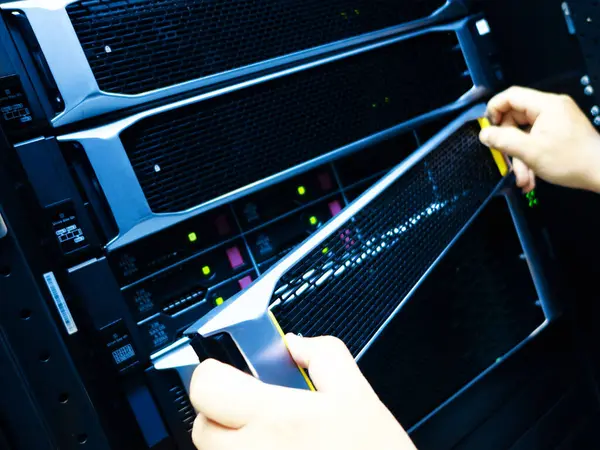 Bu resim, bir veri merkezindeki sunuculara bakım yapan bir teknisyenin ellerini gösteriyor..