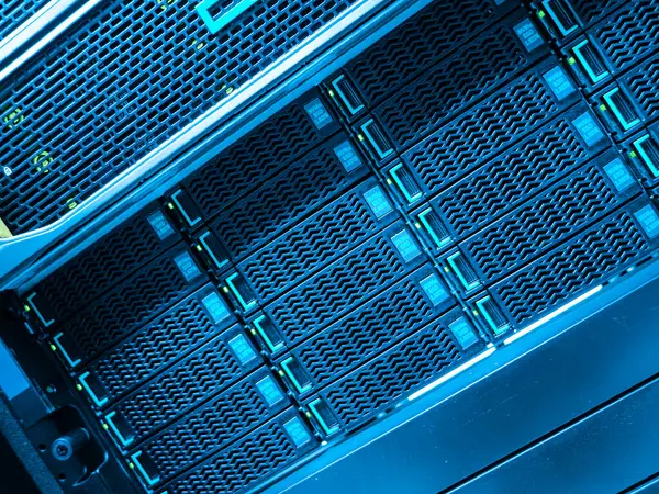 Yüksek teknolojili depolama birimlerini gösteren bir veri merkezi sunucu rafının yakın görüntüsü. Mavi ışıklandırma veri işlemede kullanılan gelişmiş teknolojiyi vurgular.