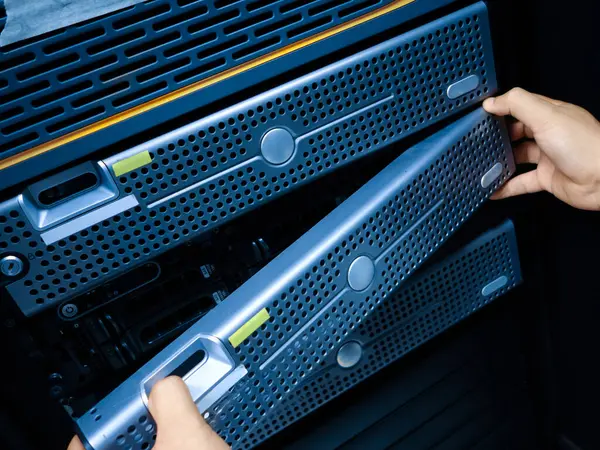 Bir teknisyen, modern teknoloji altyapısındaki donanım yönetiminin önemini vurgulayarak, bir veri merkezinde bulunan sunucuların bakımını üstlenir..