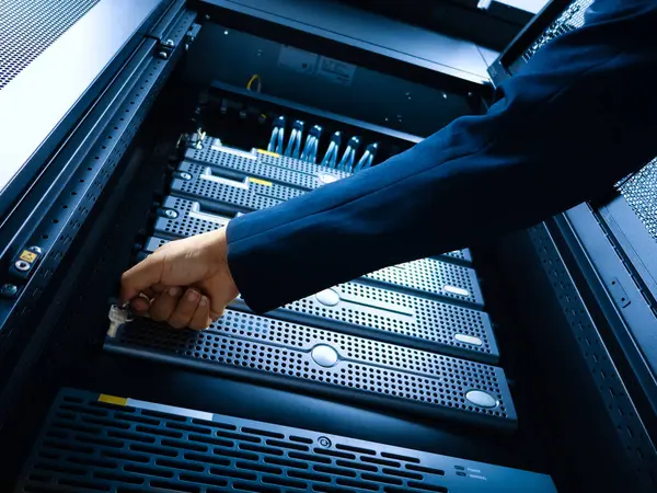 Bir teknisyen veri merkezi rafında sunucuları ayarlar, teknoloji altyapısı ve işletmelerinde bakım ve yönetimin önemini vurgular.