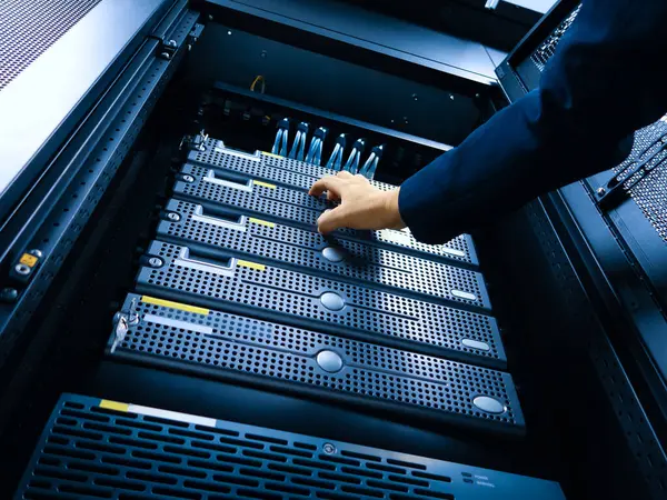 Bir teknisyen modern bir veri merkezinde sunucularda bakım yapar. Resim, optimum dijital işlemler için hayati önem taşıyan karmaşık donanım ve yönetim sürecini yakalar.