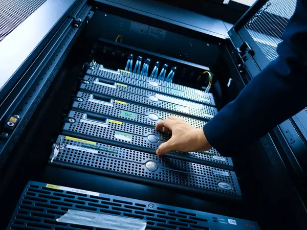 Bir teknisyen modern bir veri merkezinde sunucularda bakım yapar. Görüntü, güvenli bir ortamda teknolojiyi ve dikkatli işleyişi vurguluyor.