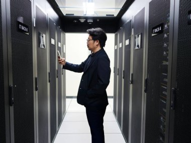 Bir bilişim uzmanı modern bir veri merkezinde sunucu raflarıyla etkileşime girer, bilgi yönetimi alanında teknoloji ve operasyonel mükemmelliğin bir karışımını sergiler.