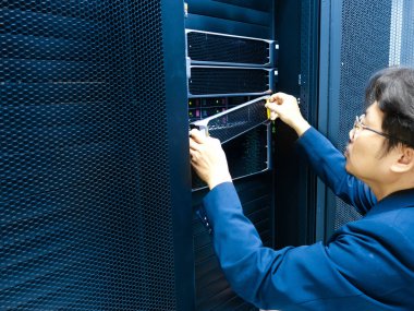 Bir teknisyen veri merkezindeki sunucuları yapılandırmaya odaklanır. Resim bakım ve sistem yönetimi için kullanılan araçları ve ekipmanları vurgular.