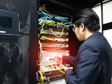 Bir teknisyen, modern veri merkezlerinin karmaşıklığını vurgulamak için bir sunucu rafı içinde bakım yapar. Odaklanmada teknoloji ve altyapı vurgulanıyor.